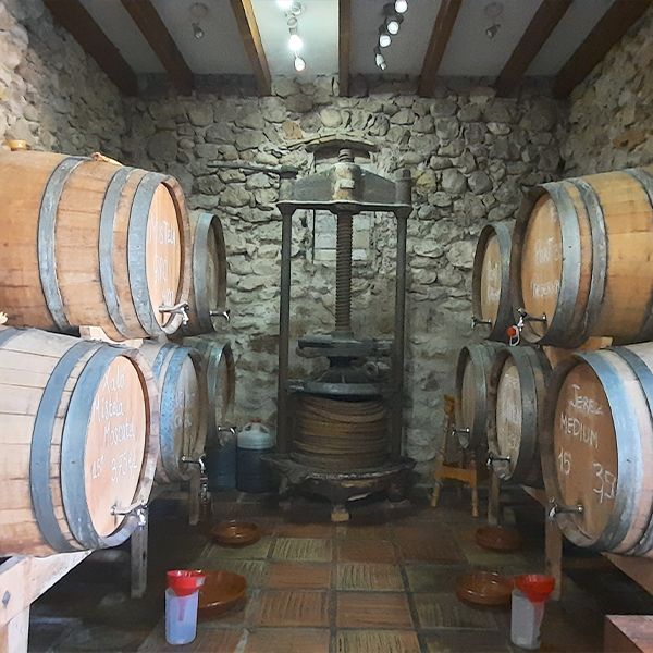 Authentieke houten wijnvaten en een antieke wijnpers in een traditionele stenen bodega in de Jalon Vallei, vlak bij investeringsproject Cala Natura Benissa.