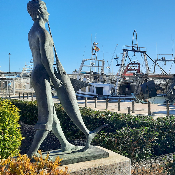 Bronzen standbeeld van een visser in de haven van Denia, symbool voor de lokale topgastronomie en vissersvloot, op korte afstand van Cala Natura Benissa.